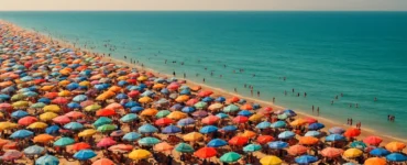 Vista panorámica de una playa llena de sombrillas durante el fenómeno del afelio, representando el calor del verano sin mostrar al Sol directamente.